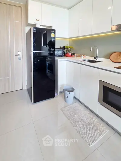 Modern kitchen with sleek appliances and minimalist design, featuring a black fridge and built-in oven.