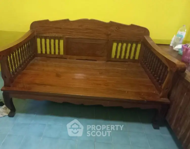Elegant wooden bench with intricate design against a vibrant yellow wall, perfect for cozy interiors.