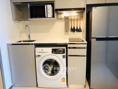 Modern compact kitchen with washing machine and microwave in sleek apartment.