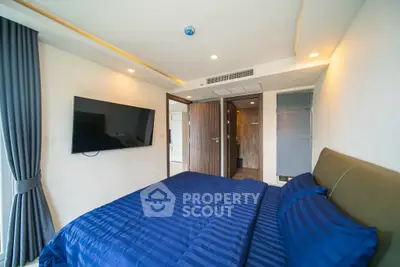 Modern bedroom with blue bedding, wall-mounted TV, and sleek design.