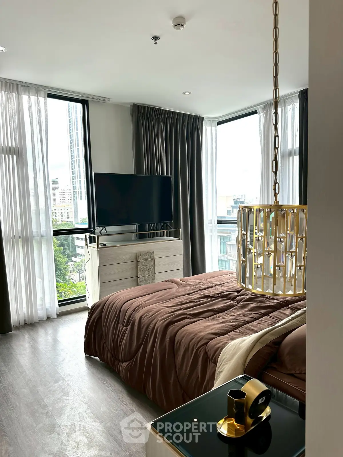 Luxurious bedroom with modern decor and city view, featuring elegant lighting and sleek furnishings.