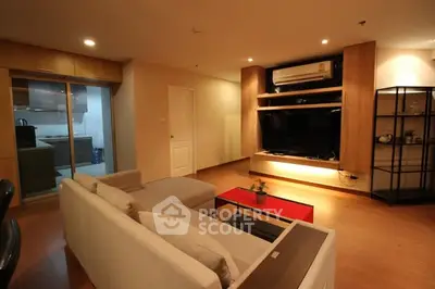 Modern living room with cozy seating and large TV, open layout to kitchen, perfect for relaxation.