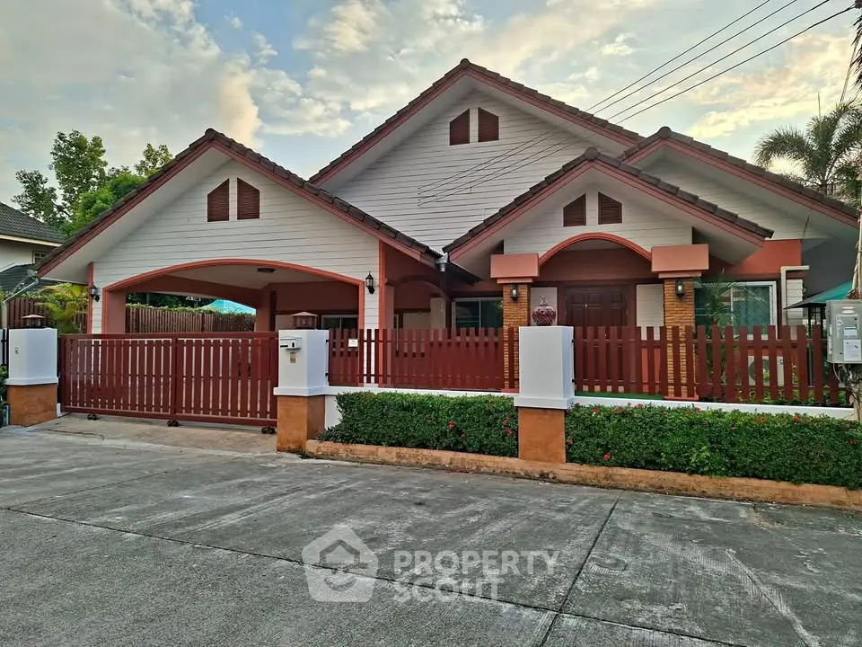 Charming suburban house with red fence and lush greenery, perfect for family living.