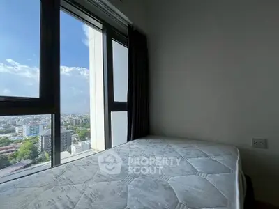 Cozy bedroom with large window offering stunning city views, perfect for urban living.
