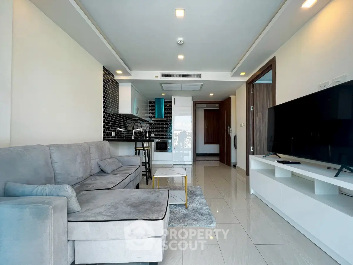 Modern living room with open kitchen, sleek design, and cozy sofa in a stylish apartment.
