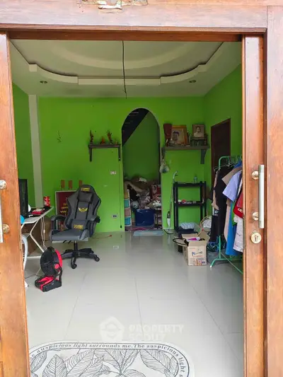 Spacious room with vibrant green walls, modern gaming chair, and organized storage shelves.