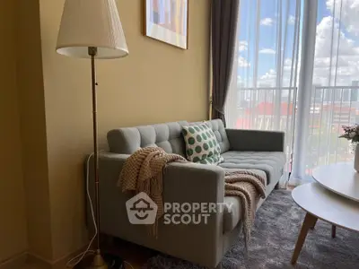 Cozy living room with stylish sofa, floor lamp, and large window offering city views.