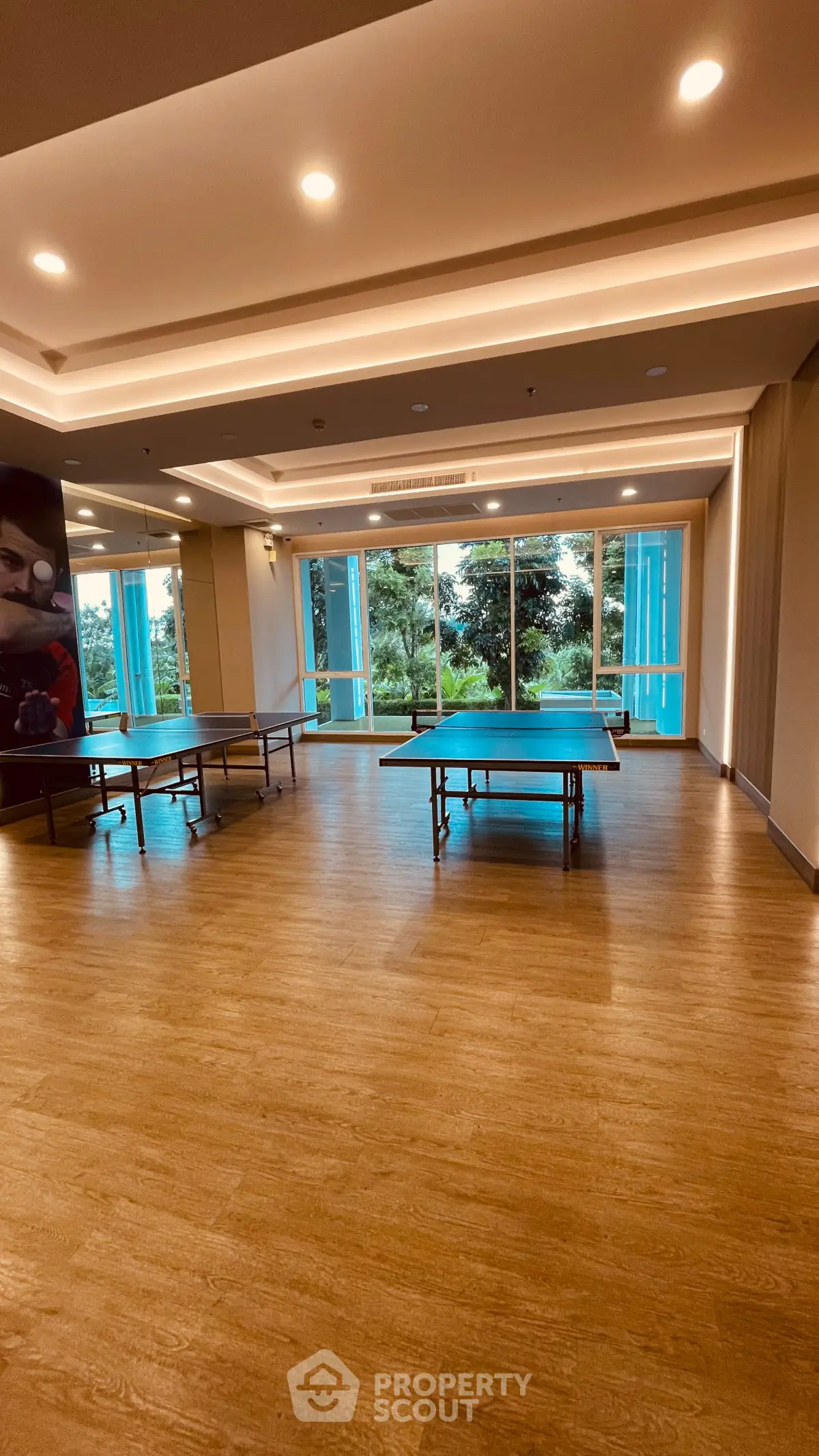 Spacious recreational room with table tennis setup and large windows offering lush garden views.