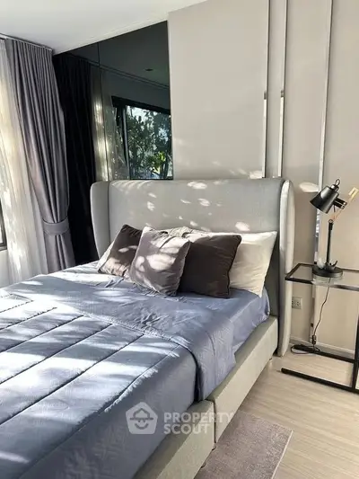 Modern bedroom with stylish decor and natural light, featuring a cozy bed and elegant furnishings.