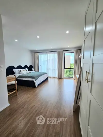 Spacious bedroom with modern decor and large window offering natural light and serene views.