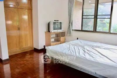 Cozy bedroom with wooden wardrobe and vintage TV in bright apartment