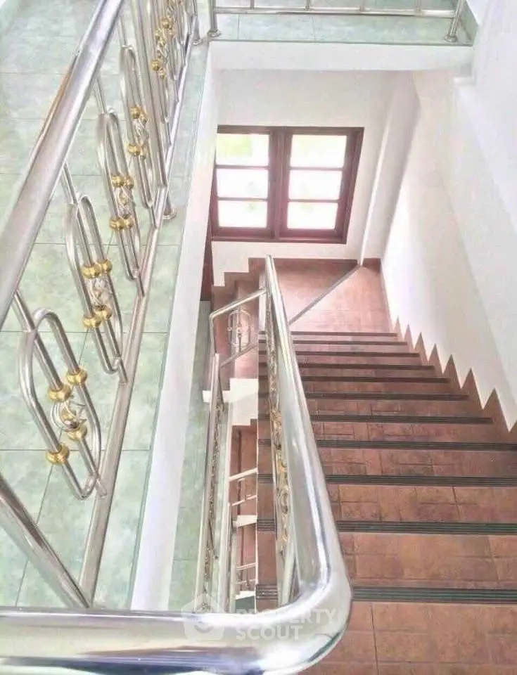 Elegant staircase with modern railings and tiled steps in a bright residential building.