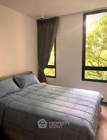 Cozy bedroom with large windows and lush green view, perfect for relaxation.