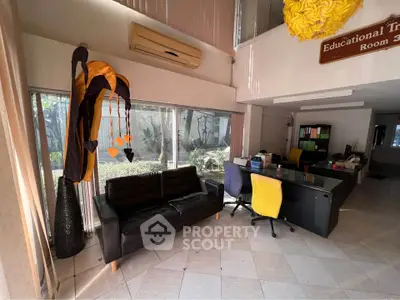 Spacious office lobby with modern furniture and large windows offering garden views.