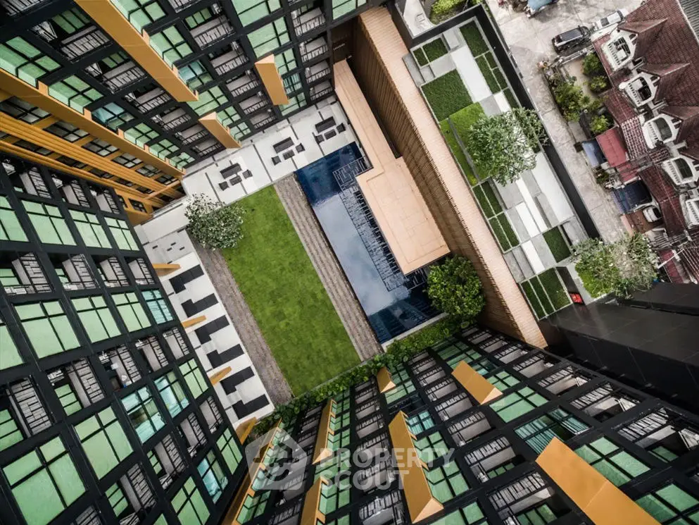 Stunning aerial view of modern apartment complex with central pool and lush green courtyard.