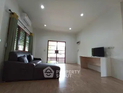 Spacious living room with modern sofa and natural light, ideal for relaxation.