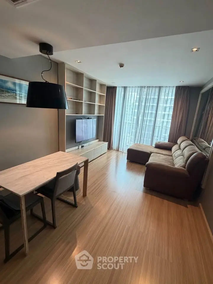 Modern living room with large windows and cozy seating area in a stylish apartment.