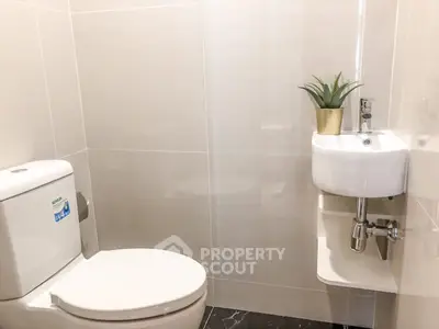 Modern minimalist bathroom with compact sink and toilet, featuring sleek design and neutral tones.
