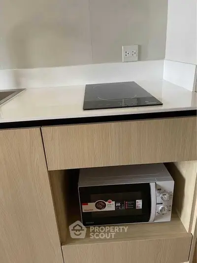 Modern kitchen with sleek induction cooktop and built-in microwave in stylish cabinetry.