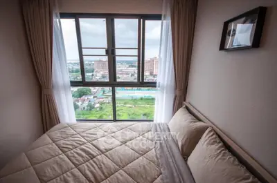 Cozy bedroom with panoramic city view through large window, featuring elegant curtains and modern decor.