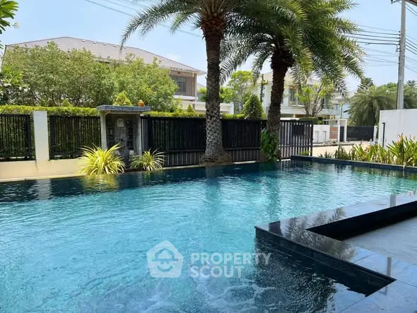 Luxurious outdoor pool with palm trees and modern fencing in a serene residential area.