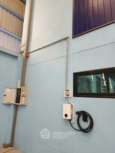 Industrial facility interior with electrical panel and charging station