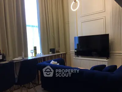 Elegant living room with plush blue sofa, modern TV setup, and stylish dining area.