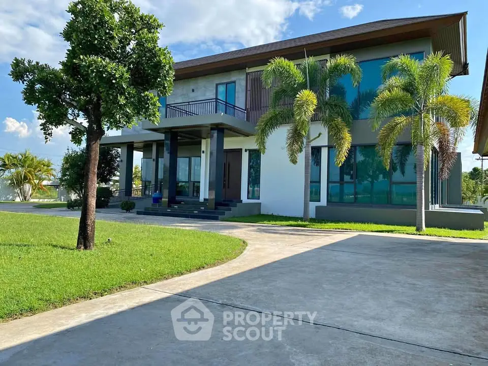 Stunning modern two-story house with large windows and lush green lawn, perfect for luxurious living.