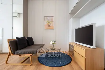 Modern living room with stylish furniture and wooden flooring, featuring a cozy sofa and a sleek TV unit.