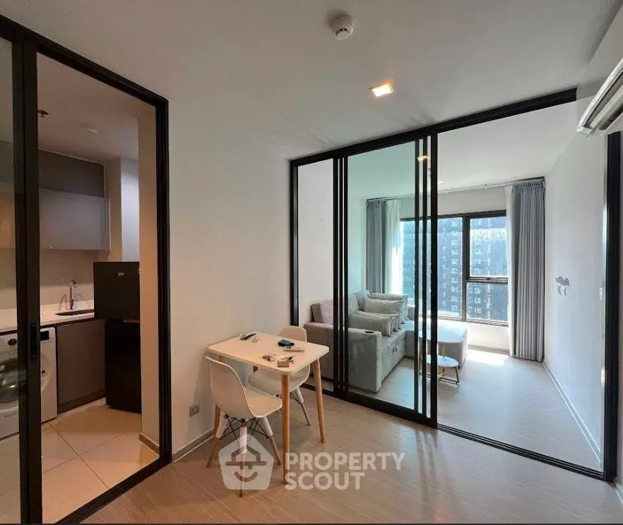 Modern apartment with open living and dining area, featuring glass sliding doors and natural light.
