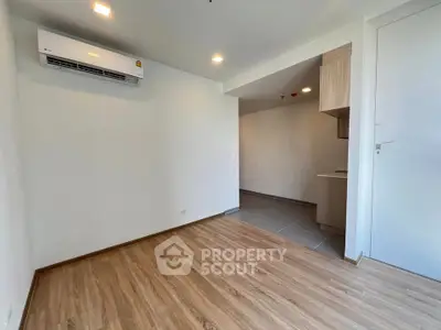 Modern apartment interior with wooden flooring and air conditioning unit, featuring a compact kitchen area.