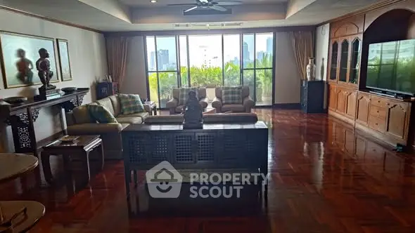 Spacious living room with elegant decor and city view, featuring large windows and polished wooden floors.