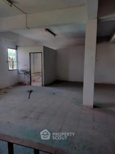 Spacious unfinished room with tiled floor and small sink area, ideal for customization.