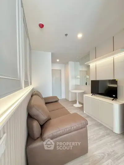 Modern living room with sleek design, featuring a comfortable sofa and a flat-screen TV, perfect for relaxation.