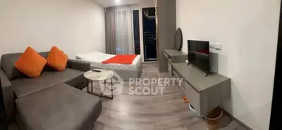 Modern studio apartment with cozy living area and bed, featuring sleek furniture and large windows.