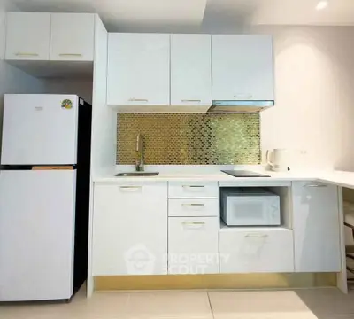 Modern kitchen with sleek white cabinets, mosaic backsplash, and built-in appliances.