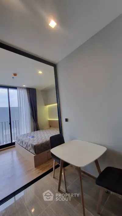 Modern studio apartment with cozy bedroom and dining area, featuring a balcony with natural light.