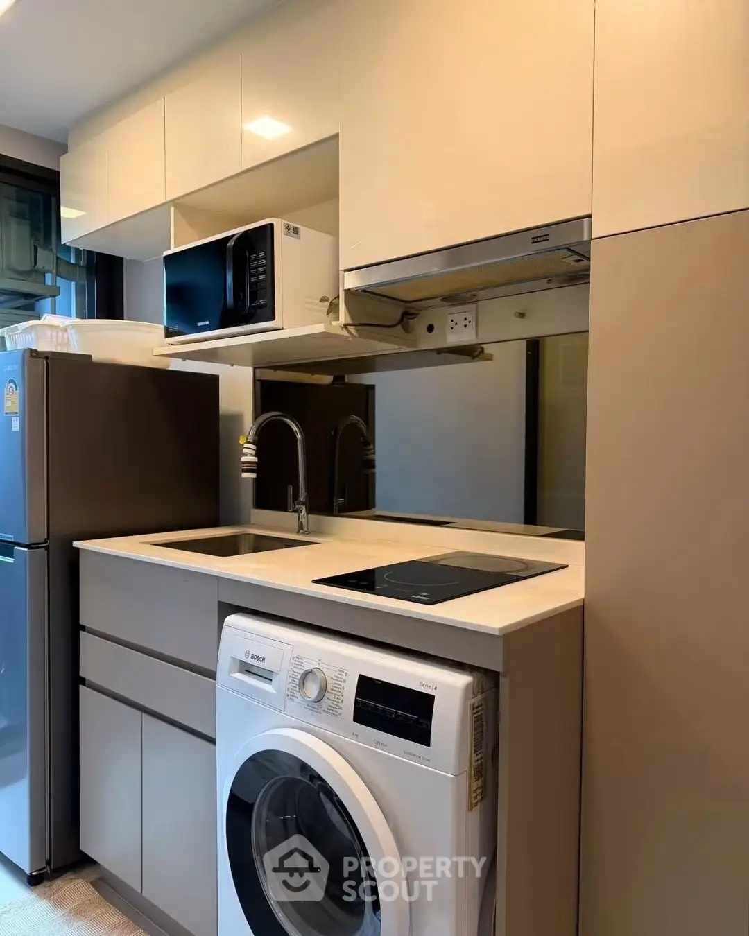 Modern kitchen with washing machine, microwave, and sleek cabinetry