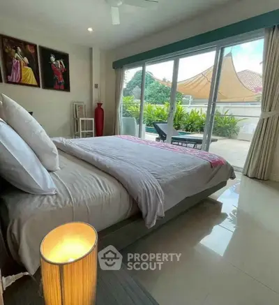 Luxurious bedroom with large glass doors opening to a private terrace with lush greenery.