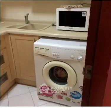 Compact kitchen with washing machine and microwave, ideal for efficient living.