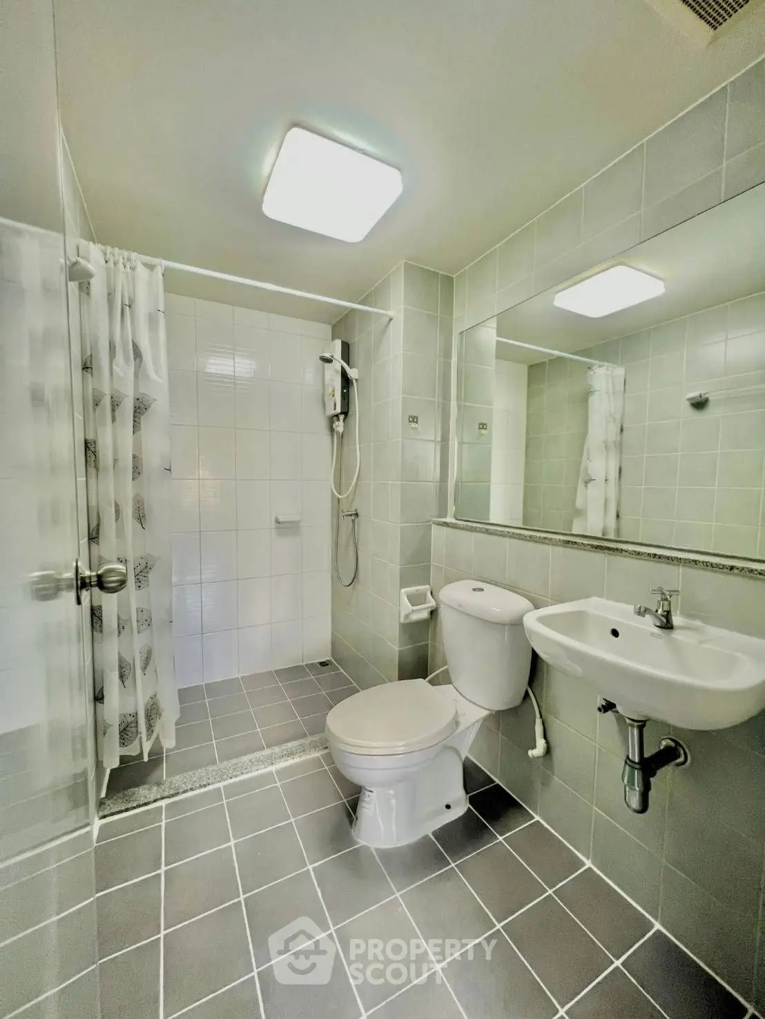 Modern bathroom with shower, toilet, and sink in sleek gray and white design.