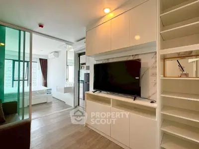 Modern apartment interior with sleek living room and bedroom, featuring built-in storage and large TV.