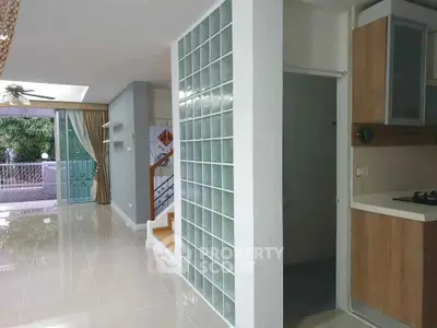 Modern open-plan living area with glass block wall and sleek kitchen design.