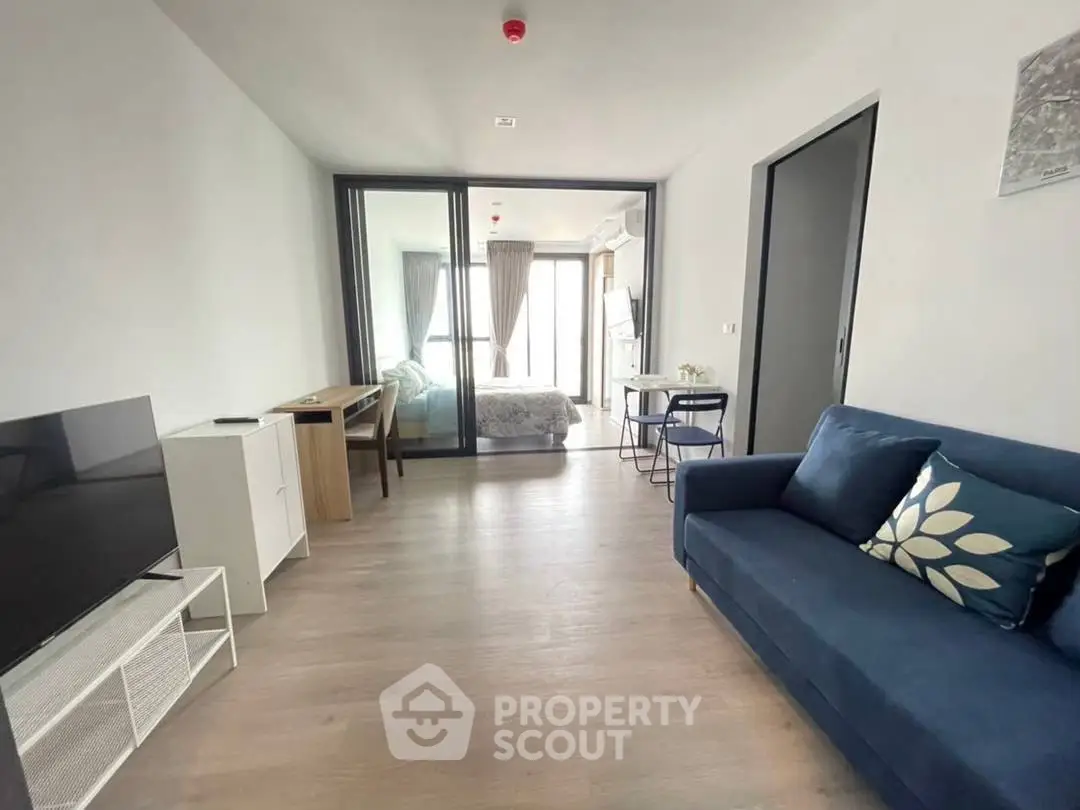 Modern living room with sleek furniture and open layout leading to bedroom.