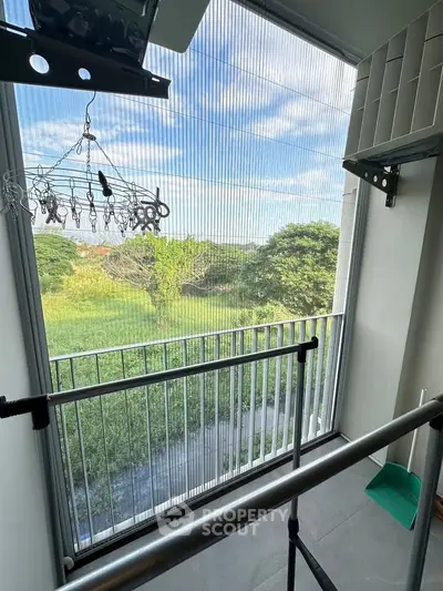 Charming balcony with lush green view and ample natural light, perfect for relaxation.