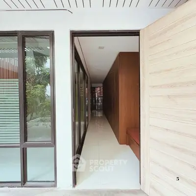 Modern hallway with glass doors and wooden accents in contemporary home.