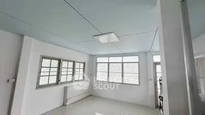 Spacious and bright room with large windows and modern lighting, perfect for versatile living space.