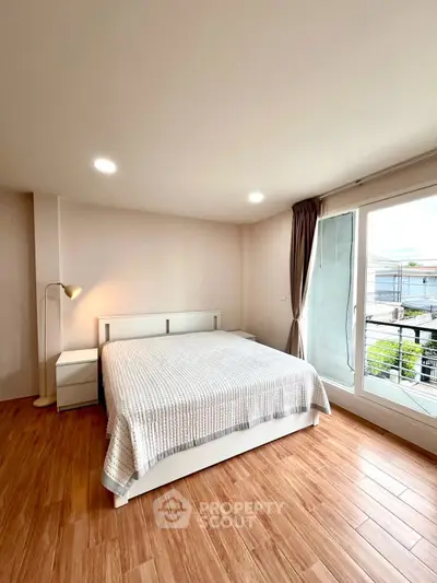 Spacious bedroom with large window and wooden flooring, offering a bright and inviting atmosphere.