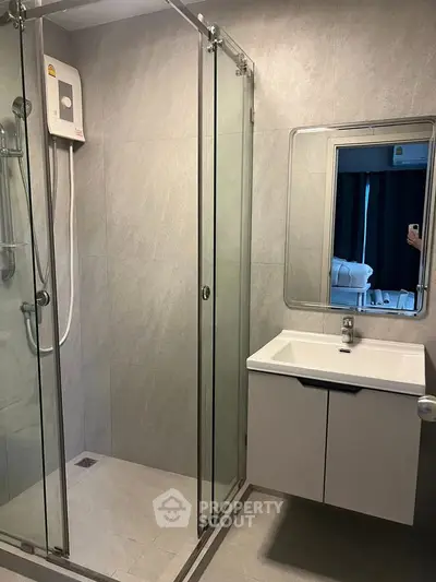 Modern bathroom with glass shower enclosure and sleek vanity in contemporary apartment.