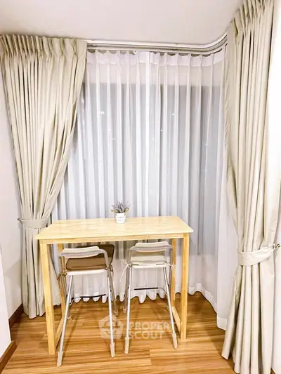 Charming corner dining nook with elegant curtains and wooden flooring, perfect for cozy meals.